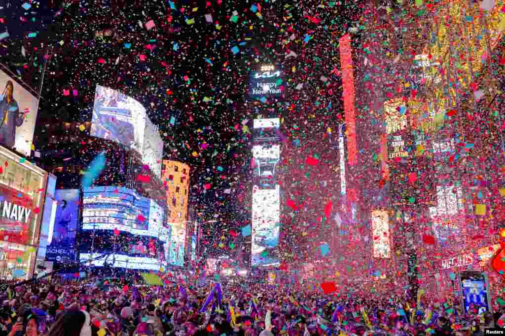 As pessoas observam os confettis a voar depois de o relógio bater a meia-noite durante as celebrações do Ano Novo em Times Square, na cidade de Nova Iorque, a 1 de janeiro de 2024.