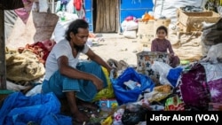 A Rohingya ragpicker and his daughter work near Delhi, India. Most Rohingya refugees do menial jobs like ragpicking for a living in India.