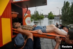 Rescuers evacuate a local resident from a flooded area after the Nova Kakhovka dam breached, amid Russia's attack on Ukraine, in Kherson, Ukraine, June 7, 2023.