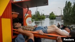 Tim evakuasi membawa seorang warga dari area banjir setelah bendungan Nova Kakhovka di Kherson hancur, pada 7 Juni 2023. (Foto: Reuters/Vladyslav Musiienko)