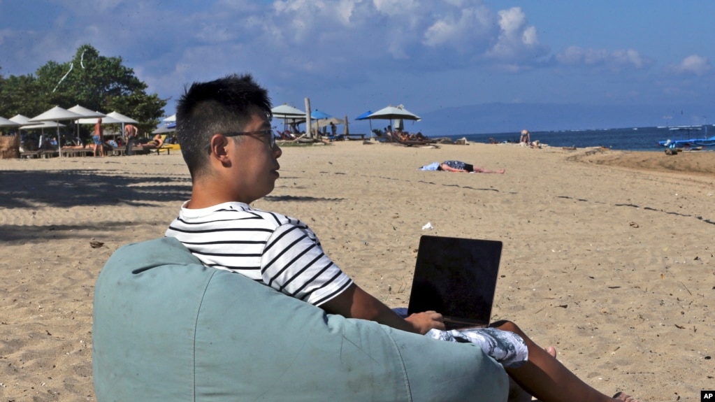 来自成都的阿莫尼奥·梁在巴厘岛海滩上使用笔记本电脑工作。(2023年6月22日)(photo:VOA)