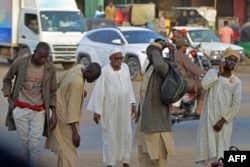 Men walk along a street in Khartoum's twin city of Umdurman, Apr. 16, 2023, Sudan's army and rival paramilitaries began an hours-long humanitarian pause on the second day of urban battles.