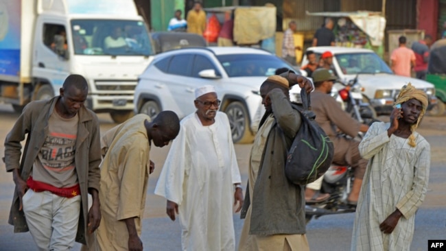 Hombres caminan por una calle en la ciudad gemela de Umdurman en Jartum, el 16 de abril de 2023, el ejército de Sudán y los paramilitares rivales comenzaron una pausa humanitaria de una hora en el segundo día de batallas urbanas.