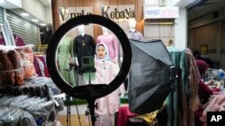 Seorang pedagang melakukan penjualan langsung melalui streaming di sebuah toko di pasar tekstil Tanah Abang di Jakarta, Kamis, 28 September 2023. (AP/Tatan Syuflana)