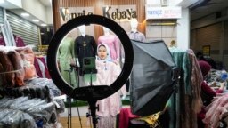 Seorang pedagang melakukan penjualan langsung melalui streaming di sebuah toko di pasar tekstil Tanah Abang di Jakarta, Kamis, 28 September 2023. (AP/Tatan Syuflana)
