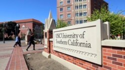 Orang-orang berjalan melintasi papan tanda di wilayah University Village di University of Southern California di Los Angeles pada 12 Maret 2019. (Foto: AP)