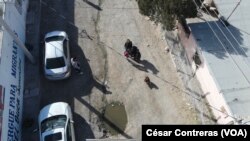 A las afueras del albergue El Buen Samaritano de Ciudad Juárez, México, niños migrantes miran hacia un dron que vuela sobre el edificio durante una visita de periodistas al área el 24 de enero 2024.