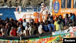 Un grupo de migrantes en una embarcación de madera son remolcados por un barco de la guardia costera española hasta el puerto de Arguineguin, en la isla de Gran Canaria, España, el 21 de octubre de 2023.