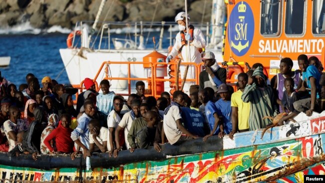 Un grupo de migrantes en una embarcación de madera son remolcados por un barco de la guardia costera española hasta el puerto de Arguineguin, en la isla de Gran Canaria, España, el 21 de octubre de 2023.