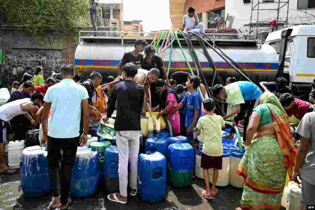 Residents fill their containers with water supplied by a municipal tanker in New Delhi, India, amid heatwave.