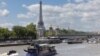 A Paris police boat (bottom left) makes its way past a cruise boat along the Seine in Paris on July 4, 2024. 