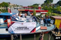 Petugas memuat kotak suara ke perahu motor sebelum didistribusikan ke Kepulauan Seribu di Jakarta, 9 Februari 2024, menjelang pemilihan presiden dan legislatif Indonesia yang dijadwalkan pada 14 Februari. (BAY ISMOYO / AFP)