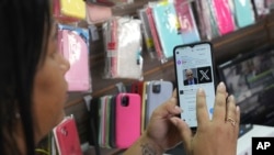 Ana Claudia, a salesperson at a cell phone case store located inside the bus station, shows the last X post she received before the social media platform was blocked nationwide in Brasilia, Brazil, Sept. 2, 2024. 