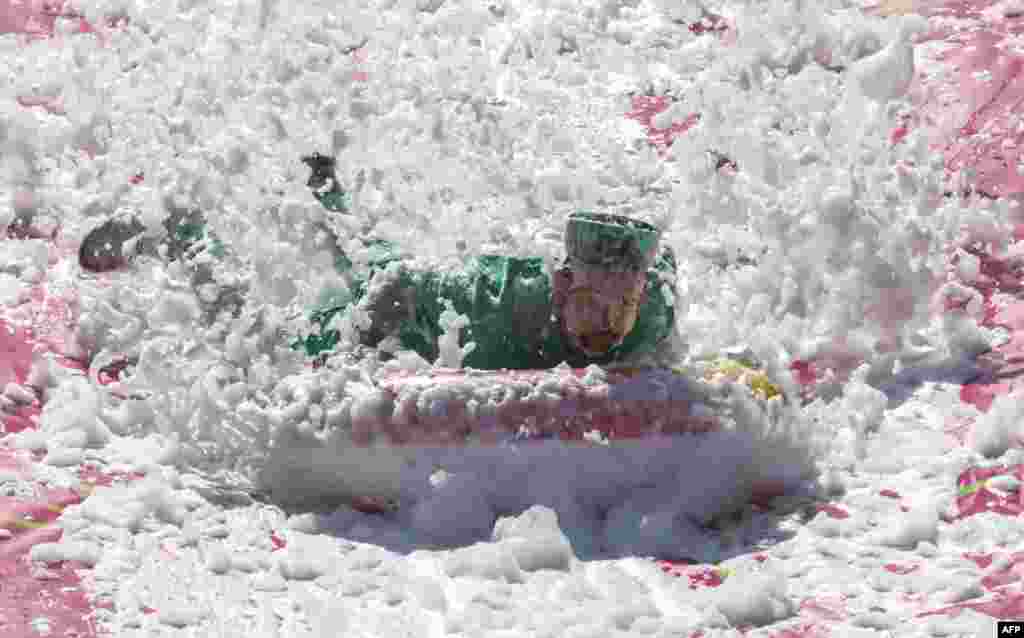 Seorang peserta bergerak menuruni seluncuran air selama kompetisi Saltibarsciai Slip and Slide selama Pink Soup Fest di Vilnius, Lithuania. (AFP)&nbsp;