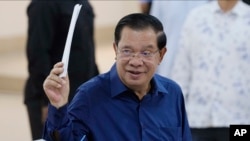 Cambodian Prime Minister Hun Sen of the Cambodian People's Party (CPP) raises a ballot before voting at a polling station at Takhmua in Kandal province, southeast Phnom Penh, Cambodia, July 23, 2023.