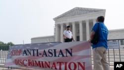 Seorang polisi mendekati anggota Asian American Coalition for Education yang berusaha memasang tanda di pagar pembatas di luar Mahkamah Agung AS di Washington, menyusul putusan tindakan afirmatif, Kamis, 29 Juni 2023. (AP/Stephanie Scarbrough)