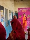 Women wait to cast their votes as one of them stands behind a selfie point during the first round of voting of India's national election in Behror, Rajasthan state, India, April 19, 2024.