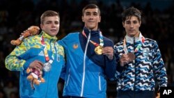 In this photo provided by the IOC, from left, Maksym Halinichev of Ukraine, Abdumalik Khalokov of Uzbekistan and Mirco Jehiel Cuello of Argentina stand during the medal a ceremony during The Youth Olympic Games in Buenos Aires, Oct. 18, 2018.