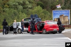 Kosovo police officers search vehicles at a cross road leading to the Banjska Monastery during a ongoing police operation in the village of Banjska, Kosovo, Sept.25, 2023.