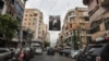 Pengendara mobil melewati poster yang menunjukkan pejuang Hizbullah yang terbunuh di pinggiran selatan Beirut, 21 Juni 2024. (ANWAR AMRO / AFP)