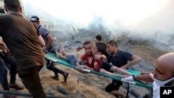 Палестинцы эвакуируют двух раненых мальчиков из-под завалов после израильских авиаударов по городу Газа, 25 октября 2023 года. (AP Photo/Абед Халед).