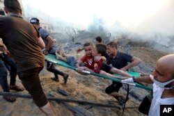Palestinians evacuate two wounded boys from rubble following Israeli airstrikes on Gaza City, Oct. 25, 2023.