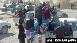 Para migran Afghanistan berdiri di atas truk pick-up saat mereka melewati jalan untuk melintasi perbatasan antara Afghanistan, Iran dan Pakistan di pinggiran Zaranj. (Foto: Wakil KOHSAR/AFP)