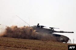 Een foto genomen in het zuiden van Israël nabij de grens met de Gazastrook op 7 december 2023 toont een Israëlische legertank die over een veld rolt te midden van voortdurende gevechten tussen Israël en de militante groep Hamas.