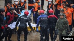 Rescue workers carry the body of a victim recovered during a search and rescue operation near an underpass that has been submerged by a flooded river caused by torrential rains in Cheongju, South Korea, July 16, 2023.