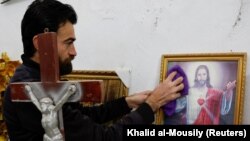 (FILE) Yezidi Christian Wael Khadida cleans the Mar Odisho Church after most Christian families fled his village in Northern Iraq.