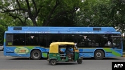 FILE - In this photograph taken on July 27, 2023, an auto rickshaw fueled by compressed natural gas (CNG) rides past an electric bus at a street in New Delhi.