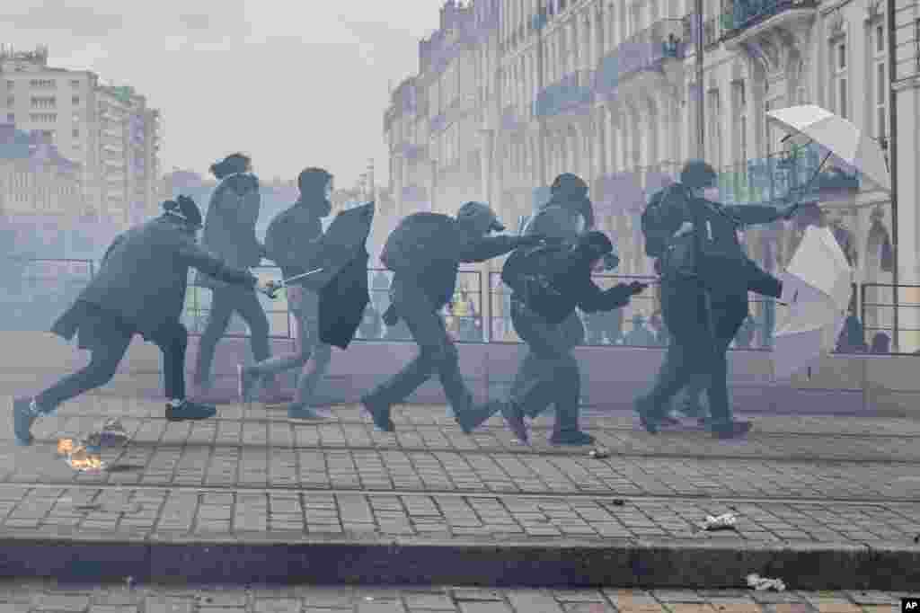 Protesters shield with umbrellas as they fight with riot police during rally in Nantes, western France.&nbsp;French unions are holding their first mass demonstrations since President Emmanuel Macron caused public anger by forcing a higher retirement age through parliament without a vote.