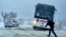 Policeman walks in front of a bus gone of the road near town of Dobrich, Bulgaria, Nov. 19 2023. Gale-force winds and heavy rain and snow hit large parts of Bulgaria, causing severe damages and disrupting power supply in towns and villages.