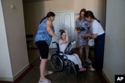 Oksana Femeniuk, left, and her daughter Solomiia receive presents from volunteers, a day after they survived a Russian missile strike on Okhmatdyt children's hospital, in Kyiv, Ukraine, July 9, 2024.