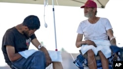 Phillip Enriquez, left, and Alfred Handley receive intravenous saline solution from a Circle The City mobile clinic, May 30, 2024 in Phoenix, Arizona.