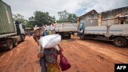  Mulher carrega alimentos distribuídos pelo Programa Alimentar Mundial (PAM) aos deslocados da província de Cabo Delgado, na Escola Tribuna 21 de abril, na vila de Namapa, distrito de Erati, Nampula, Moçambique, a 27 de fevereiro de 2024. 