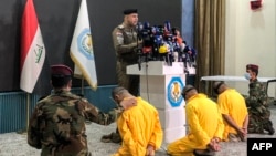 Iraqi Interior Ministry spokesman Moqdad Miri speaks before three blindfolded men during a press conference in Baghdad, July 1, 2024. Miri announced the arrest of three men accused of arson attacks in the country's north.