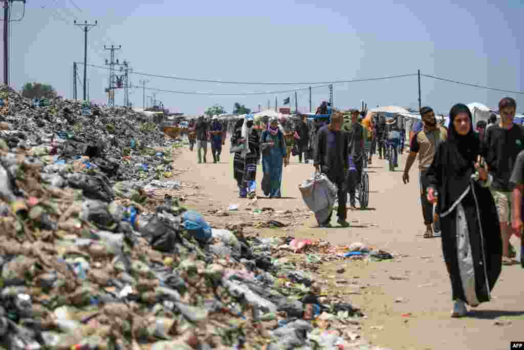 People walk on a street littered with rubbish in Khan Yunis on the southern Gaza Strip amid the ongoing conflict between Israel and the Palestinian militant group Hamas.