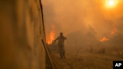 A local resident runs to avoid the flames of a wildfire in Gennadi village, on the Aegean Sea island of Rhodes, southeastern Greece, July 25, 2023.