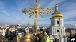 Radnici postavljaju obnovljeni krst na kupolu Katedrale sveta Sofija u Kijevu, 21. decembra 2023.