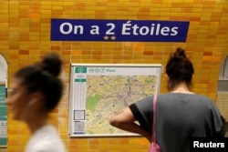 Penumpang melewati tanda metro "Charles de Gaulle - Etoile" yang berganti nama menjadi "On a 2 Etoiles" yang berarti "Kami memiliki dua bintang" satu untuk setiap kemenangan Piala Dunia di stasiun kereta bawah tanah di Paris, Prancis, 16 Juli 2018. (REUTERS/Jean-Paul Pelissier)