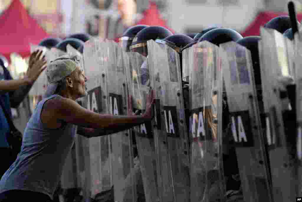 A protester pushes against riot police shields during a protest outside Congress where lawmakers are debating a bill promoted by Argentine President Javier Milei, in Buenos Aires, Jan. 31, 2024.