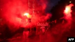 Protesters light flares during a solidarity march for the defense of immigrants against France's new immigration law at Theodor Herzl Square, in Paris.