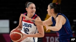 FILE - United States' Diana Taurasi (12) drives around Serbia's Sasa Cado (6) during women's basketball semifinal game at the 2020 Summer Olympics, in Saitama, Japan, Aug. 6, 2021.