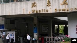 FILE - Security guards stand at an entrance to the Wanliu Campus of Peking University on May 17, 2022, in Beijing. 