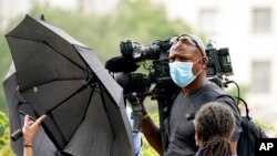 ARCHIVO - Un camarógrafo de los medios de comunicación es bloqueado con paraguas por contramanifestantes en Freedom Plaza en Washington, el sábado 18 de septiembre de 2021.