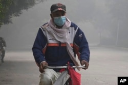 A cyclist wears a mask to protect himself against smog as he heads to work in Lahore, Pakistan, Nov. 8, 2023.