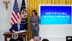 President Joe Biden signs an executive on artificial intelligence in the East Room of the White House, Oct. 30, 2023, as Vice President Kamala Harris looks on at right. 