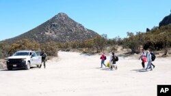 A group of asylum-seekers arrive to a makeshift camp after crossing the nearby border with Mexico, Sept. 20, 2023, near Jacumba Hot Springs, Calif.