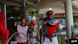 Musician and saxophonist Arundel Matoi collects a "money bouquet" from florist Mita Patel (L) for delivery to a client on Valentine's Day in Harare on February, 14 2024.